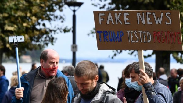A demonstrator holds up a placard reading 'Fake news - (US President Donald) Trump tested positive' to protest against masks and virus restrictions during the ongoing Covid-19 pandemic (novel coronavirus) in Konstanz, southern Germany, on October 3, 2020. SEBASTIEN BOZON / AFP