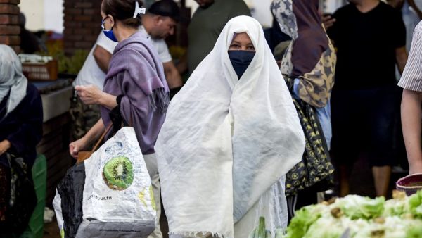 A woman clad in veil and face mask due to the COVID-19 coronavirus pandemic walks at the central market in Tunisia's capital Tunis on October 4, 2020. (AFP/File)