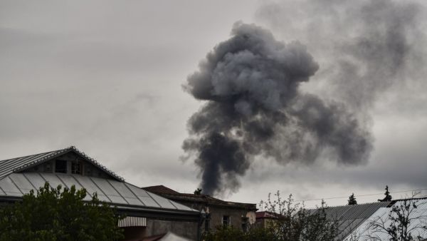 Smoke rises behind houses after shelling in the breakaway Nagorno-Karabakh region's main city of Stepanakert on October 7, 2020, during the ongoing fighting between Armenia and Azerbaijan over the disputed region. ARIS MESSINIS / AFP