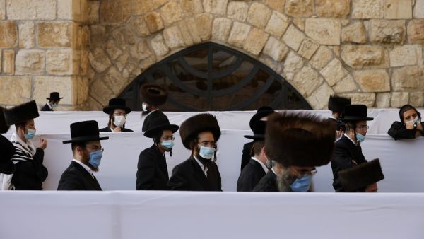 Ultra-Orthodox Jewish worshippers, wearing protective face masks, pray during the Sukkot holiday, or the feast of the Tabernacles, at the Western Wall in the old city of Jerusalem, on October 7, 2020, amid Israel's second-wave of Coronavirus lockdown. MENAHEM KAHANA / AFP