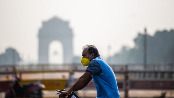 A man rides on a bicycle past India Gate amid smoggy condition in New Delhi on October 13, 2020. Jewel SAMAD / AFP