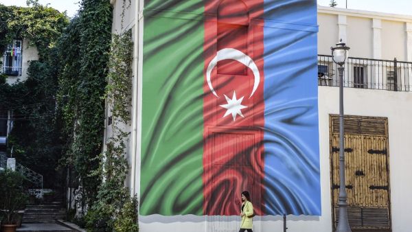 A woman walks past a building with a painting of the Azerbaijani flag on its wall in Baku on October 14, 2020, amid the ongoing military conflict between Armenia and Azerbaijan over the breakaway Nagorno-Karabakh region. TOFIK BABAYEV / AFP