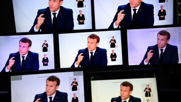 This picture shows screens displaying French President Emmanuel Macron as he addresses the nation during a televised interview from the Elysee Palace concerning the situation of the novel coronavirus Covid-19 in France, in Paris on October 14, 2020. President Emmanuel Macron on Wednesday ordered a nighttime curfew for Paris and eight other French cities to contain the rising spread of Covid-19 in the country. In a televised interview, Macron said residents of those cities would not be allowed to be outdoors