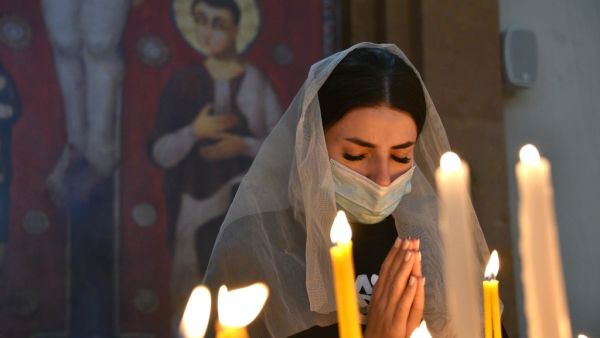 An Armenian woman, wearing a face mask, prays in a church in Yerevan on October 17, 2020, for Armenians killed during fighting over the breakaway region of Nagorno-Karabakh. Baku and Yerevan have for decades been locked in a simmering conflict over Nagorno-Karabakh, an ethnically Armenian region of Azerbaijan which broke away from Baku in a 1990s war that claimed the lives of some 30,000 people. The Caucasus neighbours have defied international calls to halt hostilities and accused the other of starting new