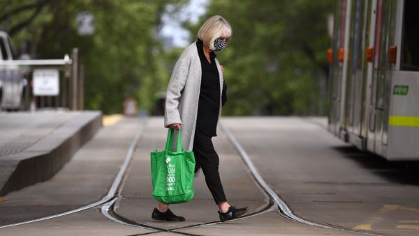 A woman crosses a street in Melbourne on October 18, 2020, as the state government announces a lifting of some restrictions as the city battles a second wave of the Covid-19 coronavirus. William WEST / AFP