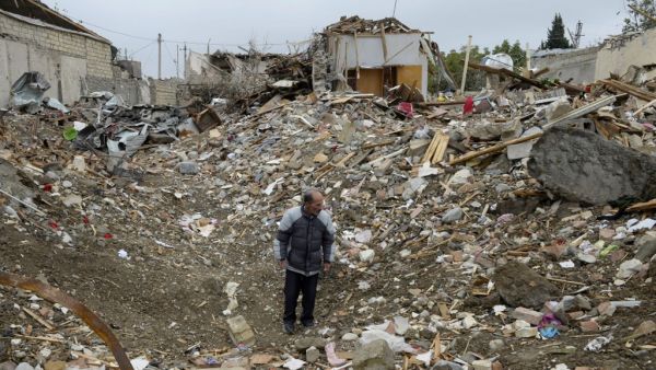 A man stands among the debris of a destroyed house hit by a rocket strike during the ongoing military conflict between Armenia and Azerbaijan over the breakaway region of Nagorno-Karabakh, in a residential area of the city of Ganja, Azerbaijan, on October 21, 2020. TOFIK BABAYEV / AFP