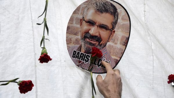  In this file photo taken on November 28, 2016 a man touches a portrait of late Kurdish lawyer Tahir Elci, displayed next to red flowers (carnations) in Diyarbakir, during a ceremony in tribute to the lawyer, near the historical mosque where he was shot dead last year. A long-awaited trial opened on October 21, 2020, of three police officers for the 2015 killing of a prominent rights lawyer in Diyarbakir, Turkey's biggest Kurdish-majority city. Tahir Elci, who campaigned for Kurdish rights, was shot in the 
