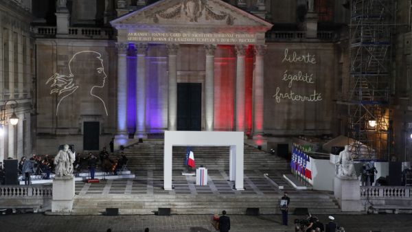 French President Emmanuel Macron, center, pays his respects in front of the coffin of Samuel Paty inside Sorbonne University's courtyard in Paris on October 21, 2020, during a national homage to French teacher Samuel Paty, who was beheaded for showing cartoons of the Prophet Mohamed in his civics class. Francois Mori / POOL / AFP