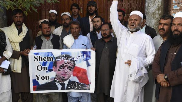 Demonstrators shout slogans and hold a poster with a picture of French President Emmanuel Macron with a footprint over his face during a protest following Macron's comments of Macron over Prophet Mohammed caricatures, in Quetta on October 26, 2020. (AFP)