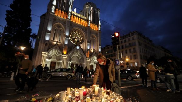 People lights candle outside the Notre-Dame de l'Assomption Basilica in Nice on October 30, 2020, a day after a knife attacker killed three people, cutting the throat of two, inside the church of the French Riviera city, and police arrest a young Tunisian migrant from Sfax who arrived in Europe only last month, according to French prosecutors. (AFP/File)