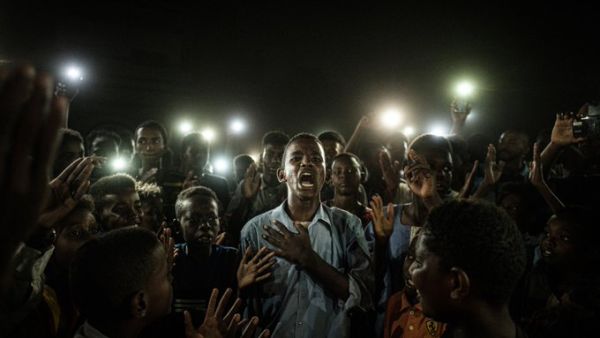 "A young man, illuminated by mobile phones, recites protest poetry while demonstrators chant slogans calling for civilian rule, during a blackout in Khartoum, Sudan." (AFP)