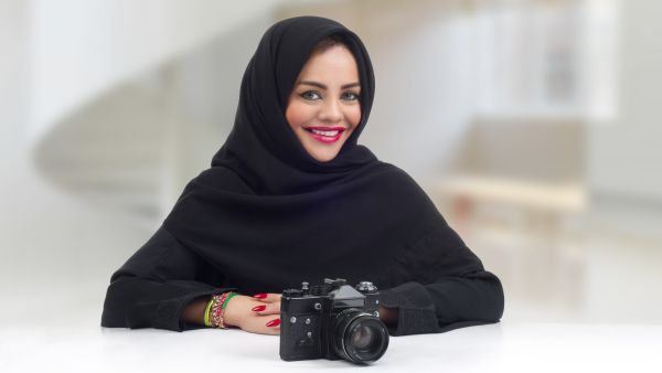 Ambitious Arabian photographer posing with her professional camera (Shutterstock)