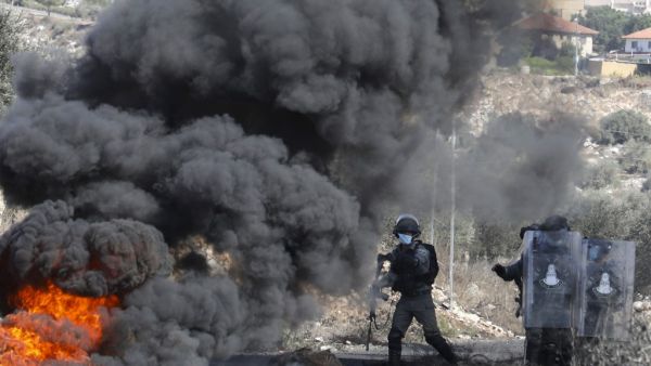 Israeli security forces take position behind burning tyres during clashes with Palestinian demonstrators at a weekly demonstration in the West Bank village of Kfar Qaddum on October 16, 2020. JAAFAR ASHTIYEH / AFP