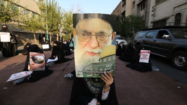 An Iranian protester holds a portrait of the supreme leader of the Islamic republic of Iran, Ayatollah Ali Khamenei, during a protest against comments made by the French president to defend secular values and cartoons mocking the prophet, outside the French embassy in Tehran on October 28, 2020. (AFP)