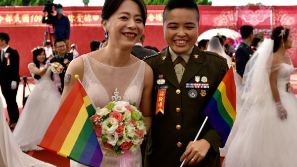 Newly-wedded same-sex couple Yi Wang (R) and Yumi Meng pose for a photograph during a mass wedding at Taiwan's Army Command Headquarters in Taoyuan on October 30, 2020, where two Taiwanese soldiers and their civilian same-sex partners tied the knot marking another gay rights landmark in Asia. Sam Yeh / AFP