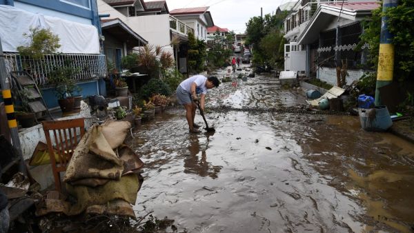 A resident shovels mud from a neighbourhood street following flooding in Batangas City on November 2, 2020, after super Typhoon Goni made landfall in the Philippines on November 1. TED ALJIBE / AFP