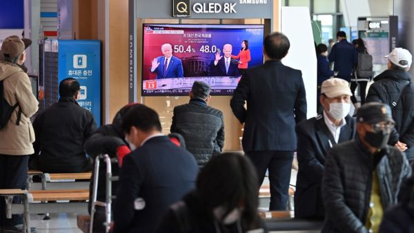 People watch a television news programme reporting on the US presidential election showing images of US President Donald Trump (L) and Democratic presidential candidate Joe Biden (R), at a railway station in Seoul on November 4, 2020. Jung Yeon-je / AFP