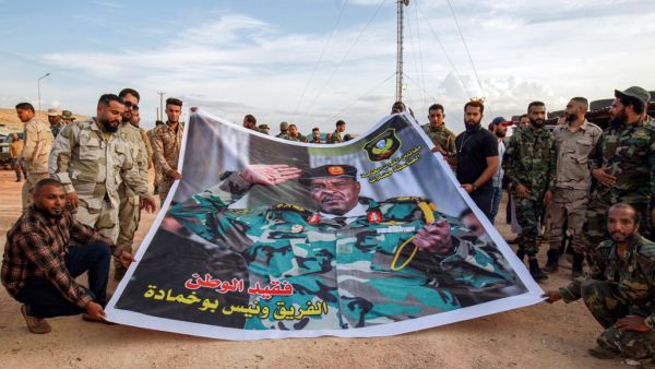 Members of the the "Saiqa" (Special Forces) of the self-proclaimed Libyan National Army (LNA), loyal to eastern strongman Khalifa Haftar, pose for a group picture with a banner depicting the unit's late commander General Wanis Bukhamada, who died a week prior, during a commemoration event in the eastern city of Benghazi on November 6, 2020. Abdullah DOMA / AFP