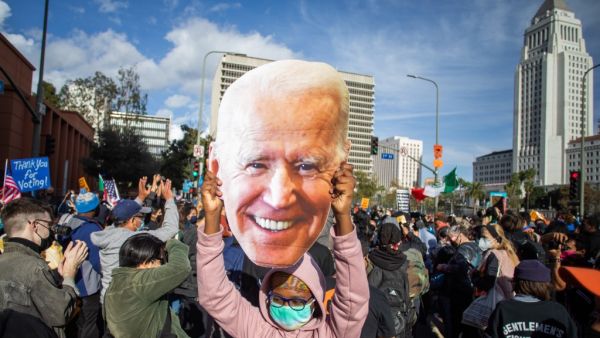 A woman holds a Joe Biden mask as people march in Los Angeles celebrating after Joe Biden was declared the winner of the 2020 presidential election on November 7, 2020. Democrat Joe Biden has won the White House, US media said November 7, defeating Donald Trump and ending a presidency that convulsed American politics, shocked the world and left the United States more divided than at any time in decades. Apu GOMES / AFP