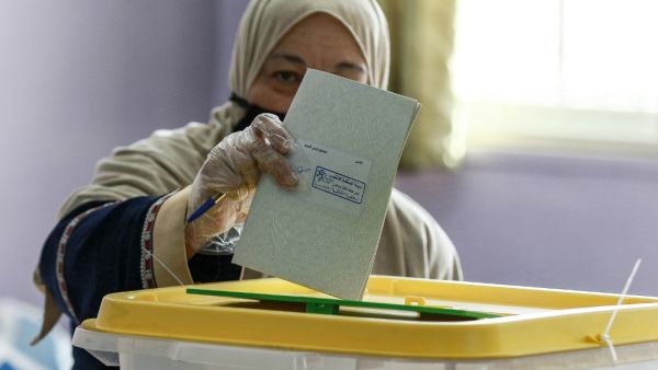 A voter, mask-clad due to the COVID-19 coronavirus pandemic, casts her ballot at a polling station in Jordan's capital Amman on November 10, 2020, during the 2020 general election. (AFP/File Photo)