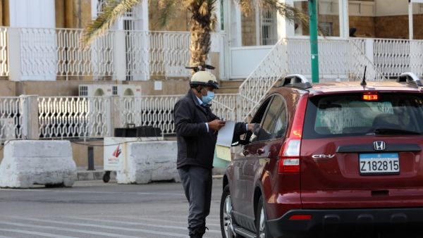 A policeman books a driver near the seaside corniche in the Lebanese capital Beirut, a day after the country went into lockdown, in a bid to stem the spread of the novel coronavirus, on November 14, 2020. AFP