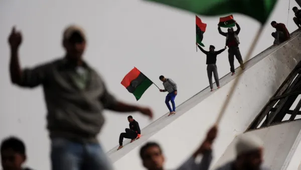 In this file photo taken on March 2, 2011, Libyans wave their old national flag as others celebrate burning copies of the “green book” authored by Libyan ruler Moamer Kadhafi, in the north-central Libyan city of Benghazi. Ten years ago, a wildfire of revolts in the Arab world touched off an unlikely series of events that swelled, then dashed many hopes, and irrevocably changed the region. ROBERTO SCHMIDT / AFP
