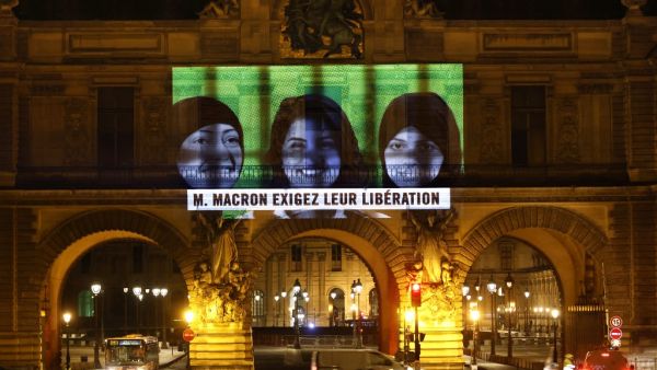 This picture taken early on November 19, 2020, shows a projection on the Louvre Museum in Paris by Amnesty International members depicting jailed Saudi human rights activists including Loujain Al-Athloul (C) and reading "Mr Macron, demand their release", ahead of the upcoming virtual G20 summit. THOMAS COEX / AFP