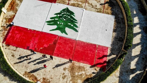This picture taken on November 21, 2020 shows an aerial view of a partially-completed 300-square-metre Lebanese national flag made up from plastic bottles, caps, and empty bullet cartridge set up by environmental activists at an open-air restaurant and wedding venue in the town of Bnachii in northern Lebanon, a day ahead of the country's 77th independence day. Ibrahim Chalhoub / AFP