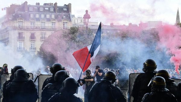 Protesters with a French flag face police during clashes on the Invalides esplanade at a demonstration in Paris. 16 June 2020 . (ALAIN JOCARD/AFP or licensors)