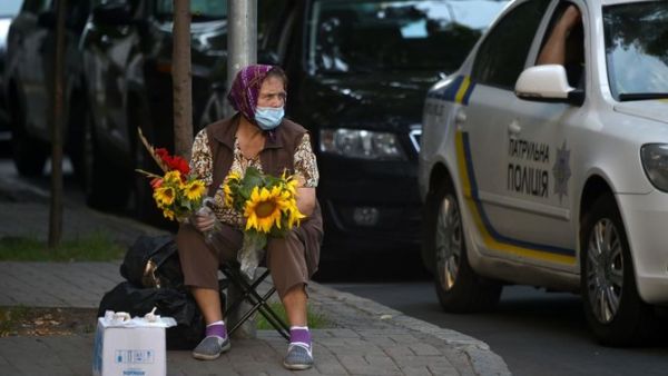 An elderly woman wearing a face mask to protect against the coronavirus disease sells flowers in the center of the Ukrainian capital of Kiev on a hot summer day on July 21, 2020. (AFP)