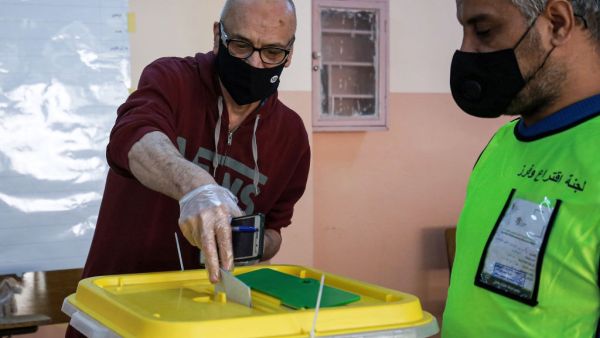 A voter, mask-clad due to the COVID-19 coronavirus pandemic, casts a ballot at a polling station in Jordan's capital Amman on November 10, 2020, KHALIL MAZRAAWI/AFP via Getty Images]