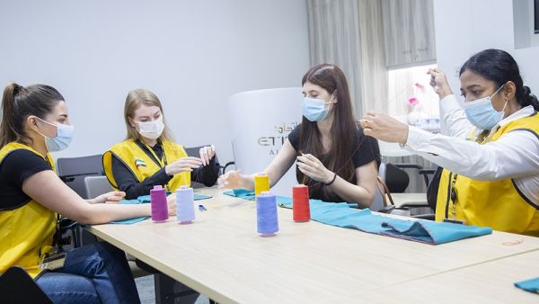 Employee from Etihad Aviation Group sewing scarves for Children in Lebanon Etihad Aviation Group Distributes 10,000 Scarves To Children in Lebanon