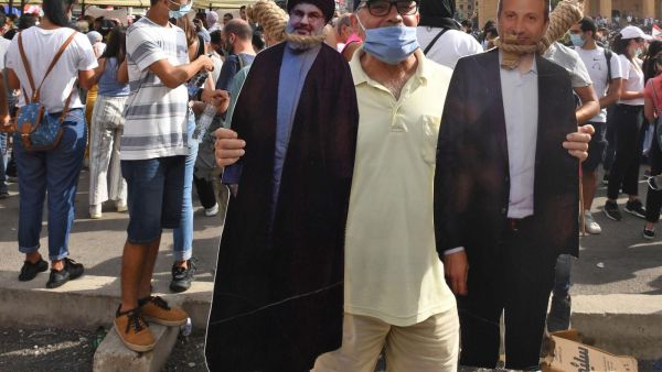 Man holds cut-outs of Hezbollah leader Hassan Nasrallah, left, and former foreign minister Gebran Bassil (AFP)
