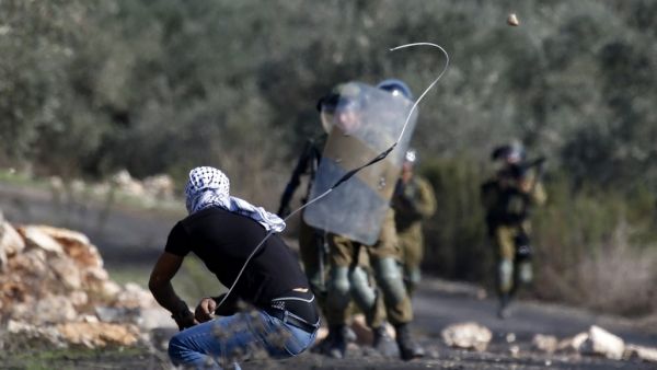 A Palestinian demonstrator uses a slingshot to hurl stones toward Israeli security forces during clashes with them following a weekly demonstration in the occupied West Bank village of Kfar Qaddum, on November 13, 2020. JAAFAR ASHTIYEH / AFP