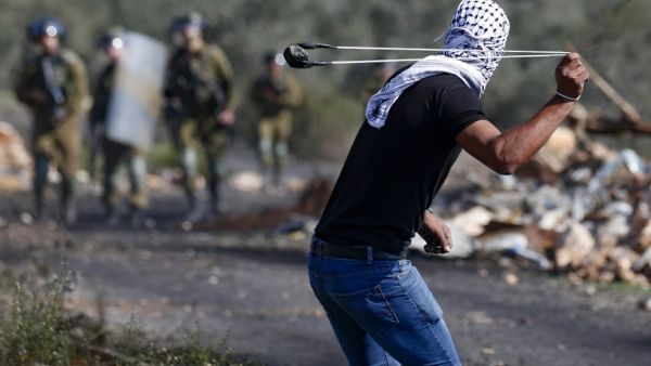 A Palestinian demonstrator uses a slingshot to hurl stones toward Israeli security forces during clashes with them following a weekly demonstration in the occupied West Bank village of Kfar Qaddum, on November 13, 2020. JAAFAR ASHTIYEH / AFP