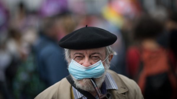 A man smokes a pipe while wearing a face mask during a demonstration in Nantes, western France, on June 30, 2020, as part of a nationwide day of protests to demand better working conditions for health workers. Loic VENANCE / AFP