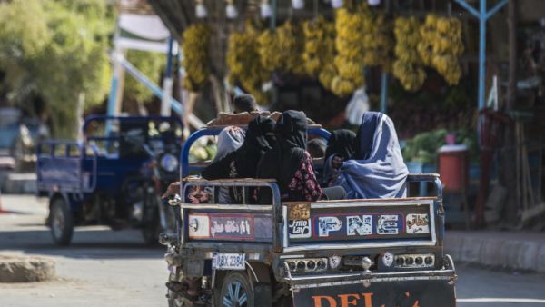 Women clad in veils sit in the back of a tricycle cart moving along a road in Egypt's western desert oasis of Siwa, some 600 kilometres from the capital, on November 6, 2020. In Egypt's western desert oasis of Siwa, the "Siwi" local Berber dialect remains clinging to life in the face of the dominance of Arabic which is used by only a few adults as their main language. AFP