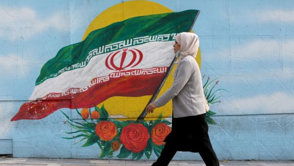 A woman walks while wearing a face mask amid the COVID-19 pandemic in the Iranian capital Tehran, on November 30, 2020. ATTA KENARE / AFP