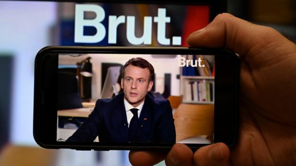 A journalist watches a live stream interview of French President Emmanuel Macron to the digital news platform Brut on December 4, 2020 in Paris. BERTRAND GUAY / AFP