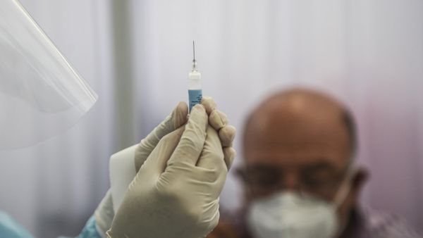 A health worker prepares a syringe to inoculate a volunteer with a COVID-19 vaccine produced by the Chinese Sinopharm during its trial at the Clinical Studies Center of the Cayetano Heredia University in Lima on December 09, 2020. ERNESTO BENAVIDES / AFP