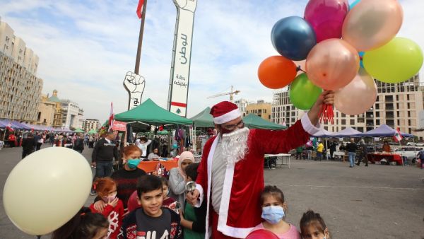 A Lebanese man wearing a Santa Claus outfit, entertains children at a Christmas market set up on Martyr's square, the epicentre of anti-government protests, in the capital Beirut's downtown district, on December 13, 2020. ANWAR AMRO / AFP