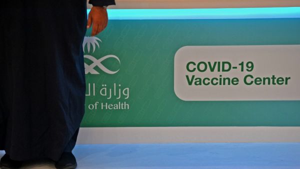 A man stands next to a sign at a location where the the Pfizer-BioNTech COVID-19 coronavirus vaccine (Tozinameran) is being administered by Saudi health authorities in the capital Riyadh on December 17, 2020. FAYEZ NURELDINE / AFP