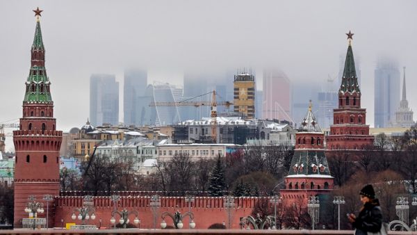 A woman walks in front of the Kremlin and skyscrapers of the Moscow International Business Centre (Moskva City) in Moscow on December 17, 2020. Yuri KADOBNOV / AFP