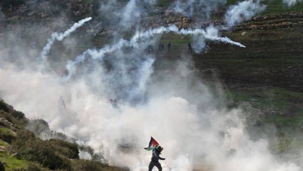 Palestinian protesters run for cover from tear gas canisters fired by Israeli security forces during a demonstration against the expansion of settlements near the West Bank village of Beit Dajan, east of Nablus, on December 18, 2020. JAAFAR ASHTIYEH / AFP
