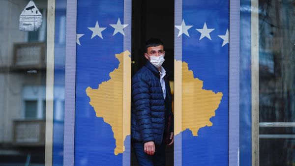 A man exits a government building decorated with Kosovo's flag in Pristina on December 22, 2020. Kosovo was preparing to call a snap poll, after its top court ruled last year's election of Prime Minister Avdullah Hoti was unconstitutional, delivering fresh upheaval to the democracy's crisis-hit politics.  Armend NIMANI / AFP