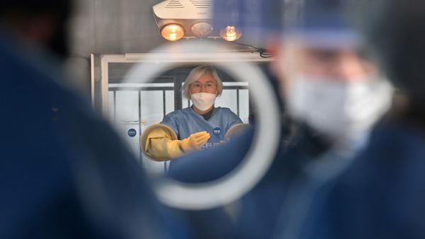 A medical staff member (C) wearing protective gear in a booth prepares to give tests for the COVID-19 coronavirus at a temporary testing station outside the City Hall in Seoul on December 23, 2020, as South Korea banned gatherings of more than four people in the capital and surrounding areas amid a surge in infection cases. Jung Yeon-je / AFP