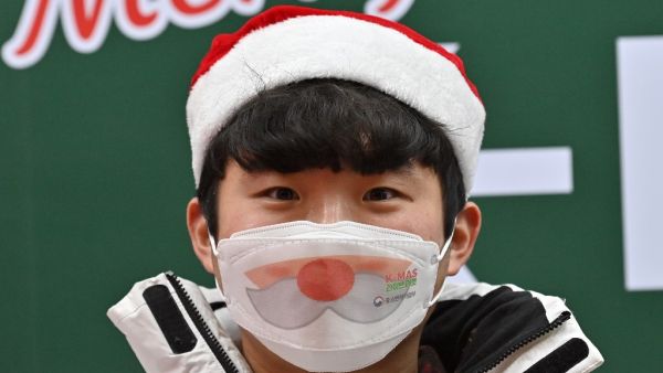 A staff member wearing a face mask stands in a Christmas-themed booth in Seoul on December 23, 2020, as South Korea banned gatherings of more than four people in the capital and surrounding areas amid a surge in cases of the COVID-19 coronavirus. Jung Yeon-je / AFP