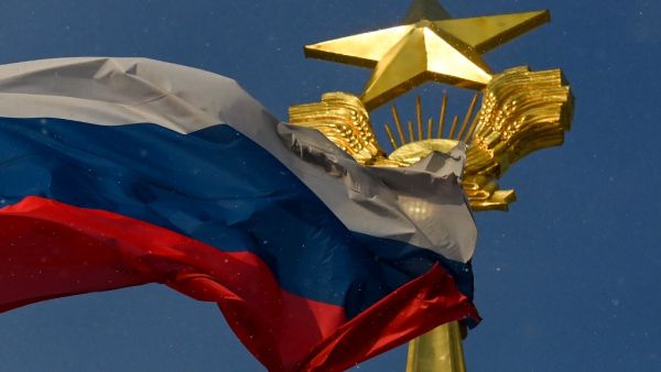 A photograph taken on December 27, 2020 shows the Russian national flag flapping on the wind in front of the Soviet Union symbols placed on the top of a building, in Moscow. Kirill KUDRYAVTSEV / AFP