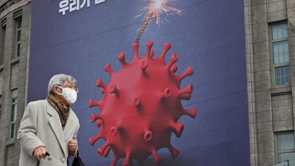 An elderly woman walks past a poster depicting the coronavirus as a bomb to warn against the Covid-19 coronavirus at the City Hall in Seoul on December 28, 2020. Jung Yeon-je / AFP