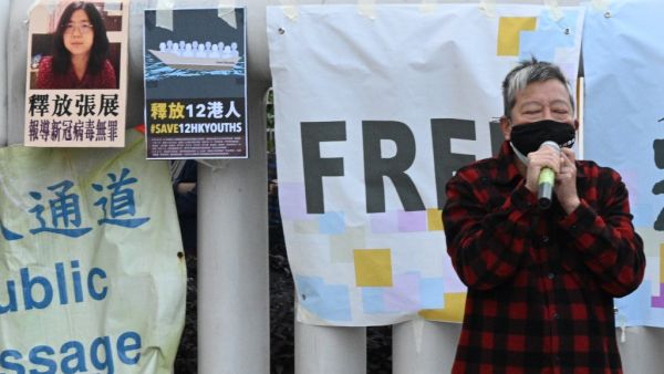 Democracy activist Lee Cheuk-Yan speaks outside China's Liaison Office in Hong Kong on December 28, 2020, during a protest calling on China to free a group of Hong Kong democracy activists facing trial in China, after they attempted to flee the territory by speedboat to Taiwan last August, as well as Chinese citizen journalist Zhang Zhan (top L poster) who was jailed for four years for her livestream reporting from Wuhan as the Covid-19 outbreak unfurled.  Peter PARKS / AFP
